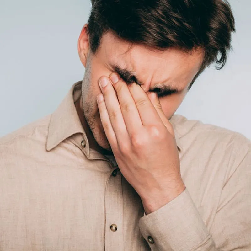 A man with eyes closed pinching the bridge of his nose