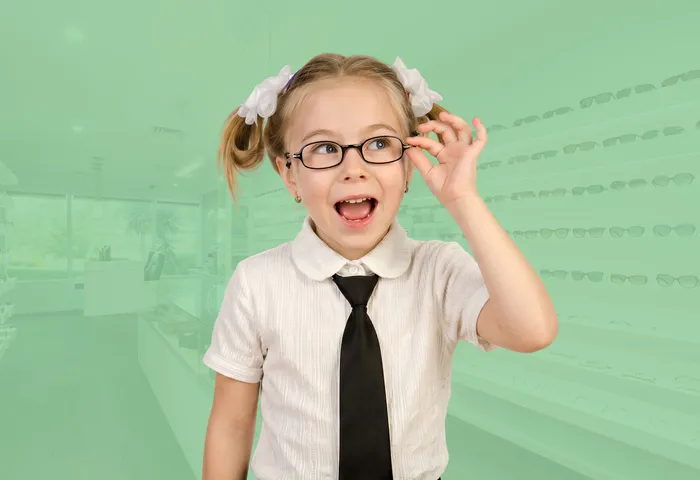 A young girl smiling and adjusting her new glasses