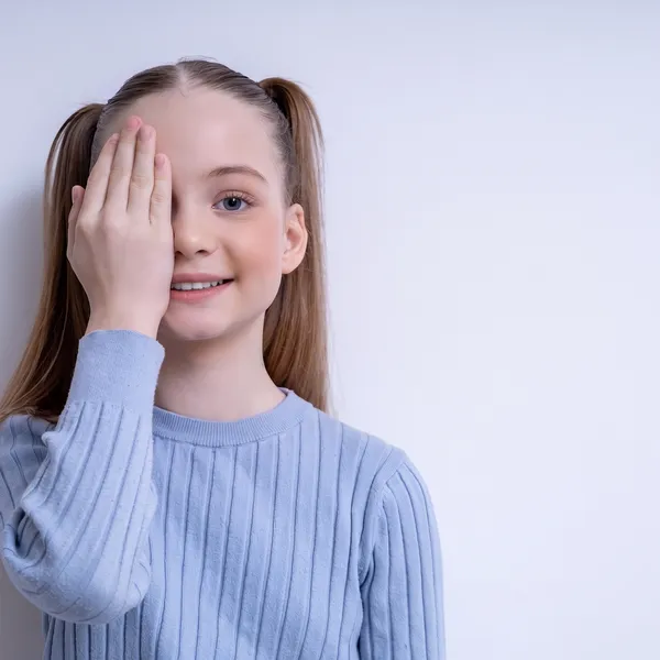 A young girl covering one eye during a vision test