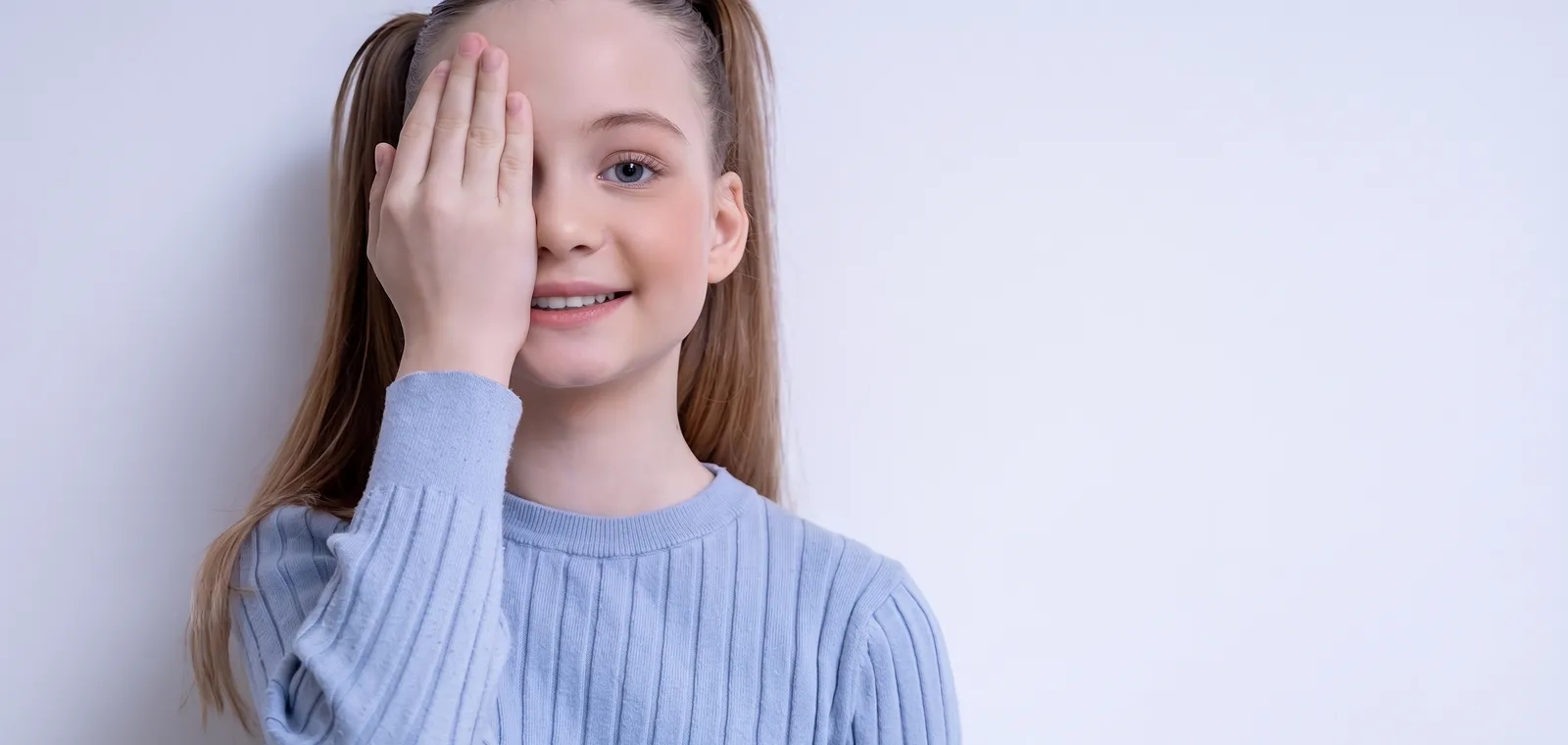 A young girl covering one eye during a vision test