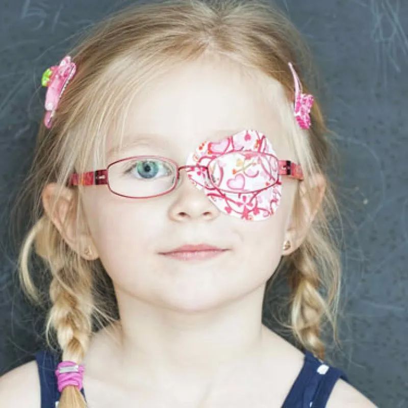 A young girl wearing glasses with a patterned patch covering one lens