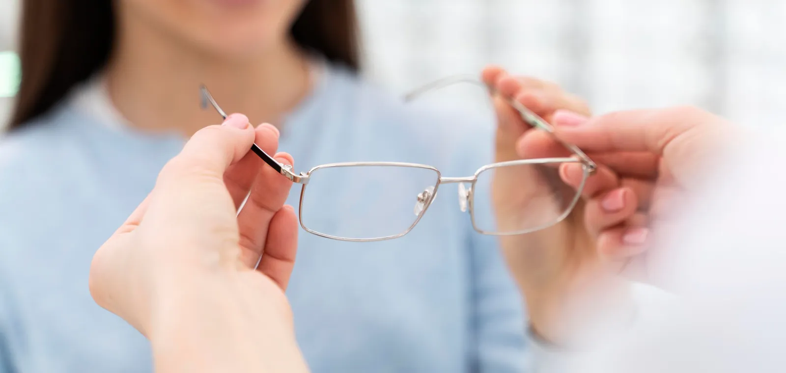 An optical assistant helping a patient try on a new pair of glasses