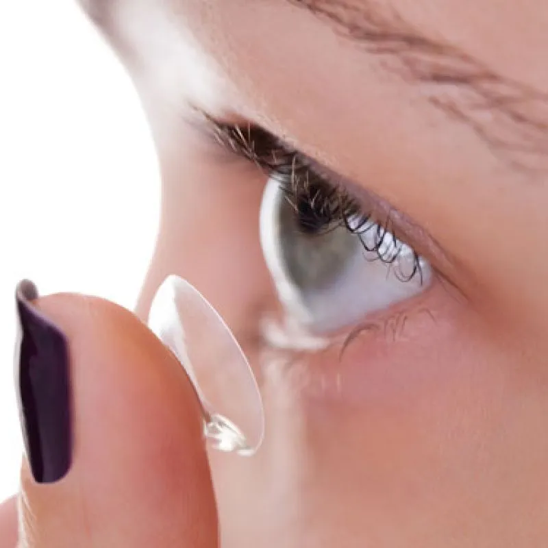 A contact lens on a fingertip being brought up to an eye