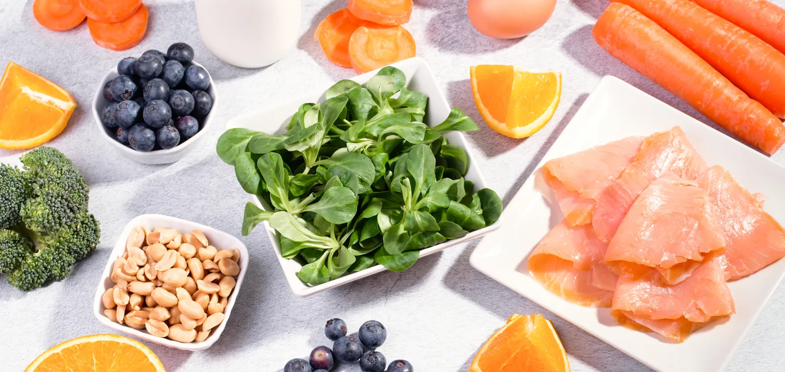 A spread of eye-healthy foods including leafy greens, salmon, and citrus