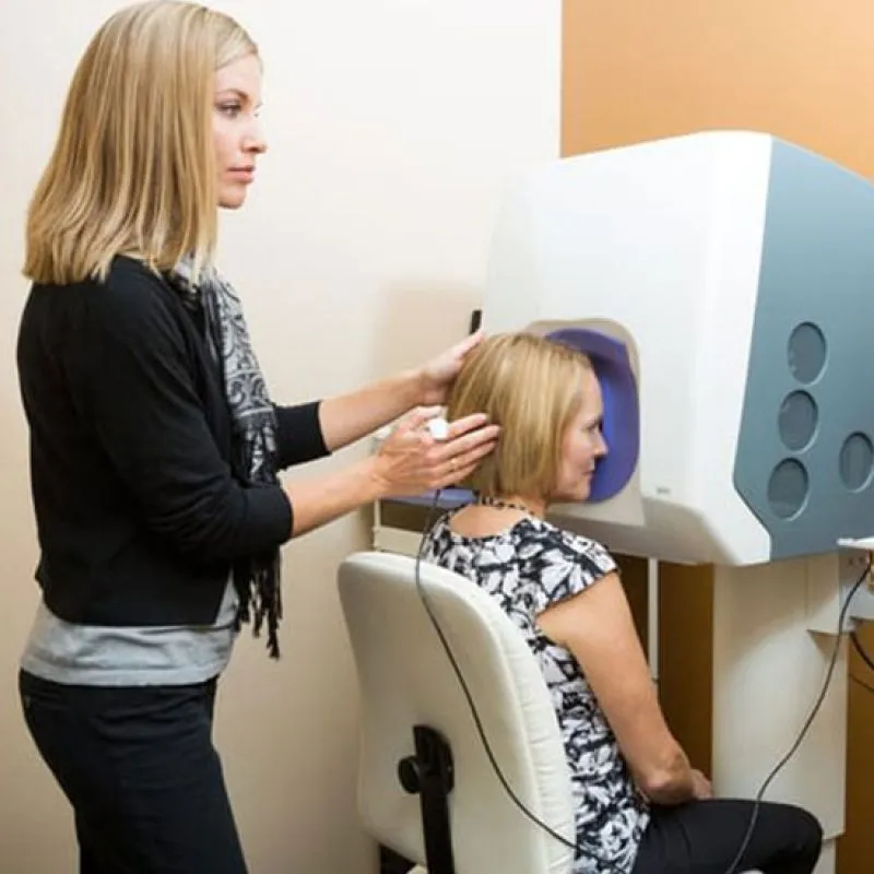 An optometrist guiding a patient at a retinal imaging machine