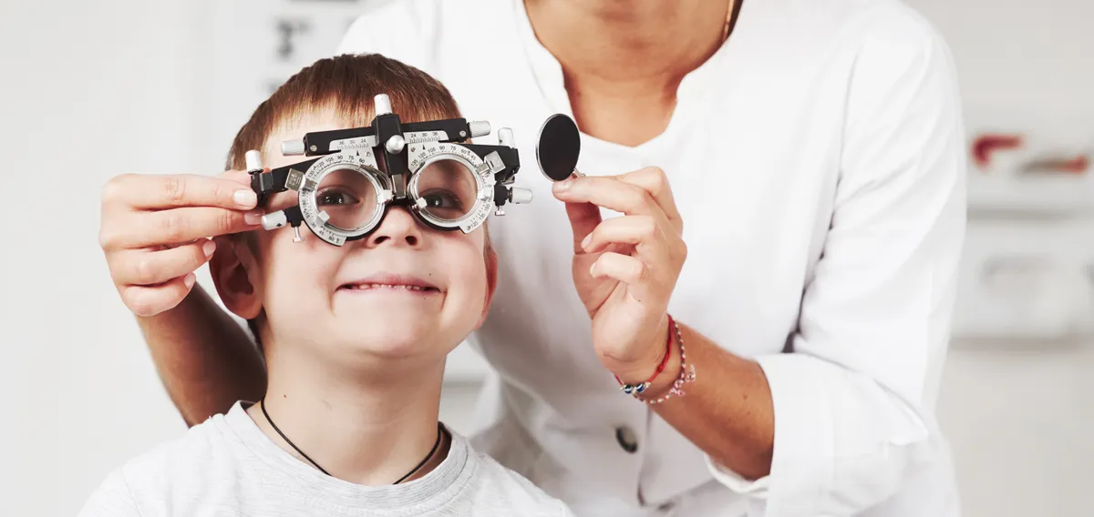 A young boy having his eyes tested with a trial frame at Outlook Eye Centre