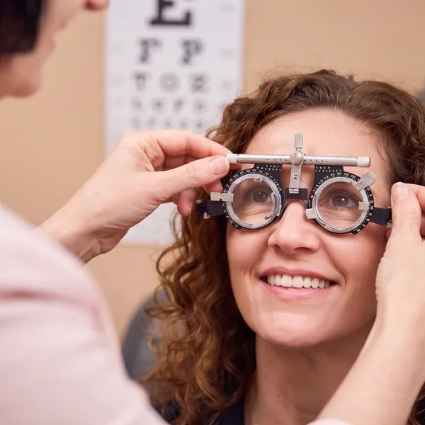 An optometrist fitting a patient with a trial frame during an eye examination