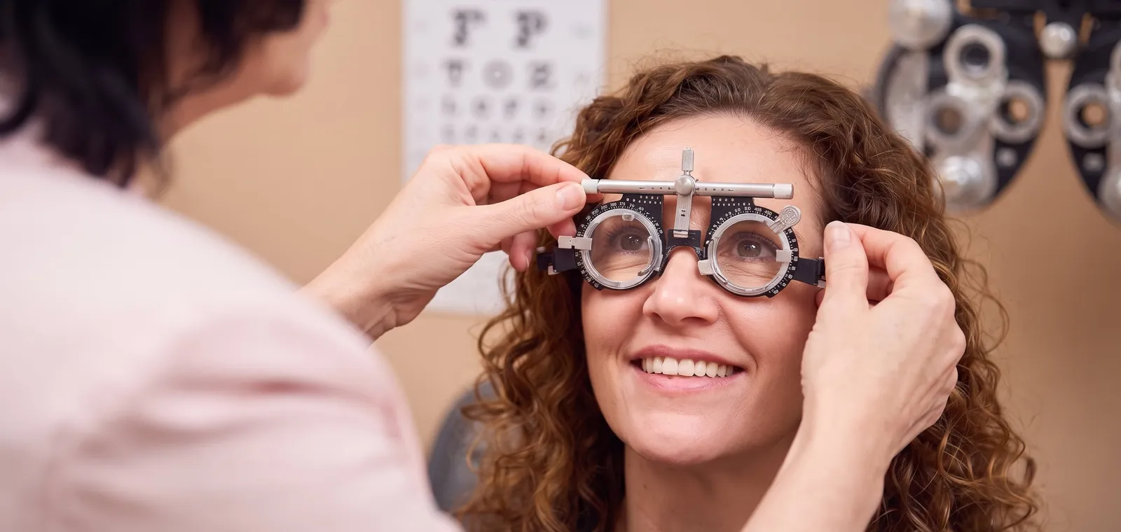 An optometrist fitting a patient with a trial frame during an eye examination