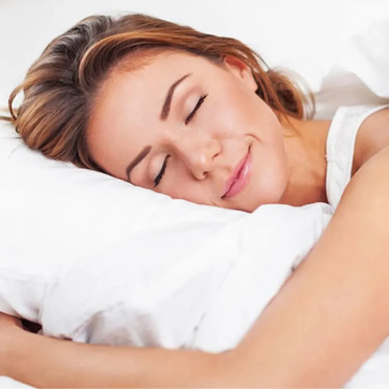 A woman sleeping peacefully on a white pillow